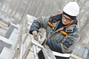 Custom Fence Installation by worker with a hard hat on and power tool